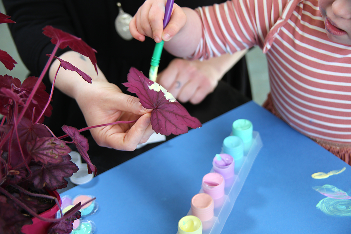Participant putting paint on a plant in Down Syndrome Ireland workshop