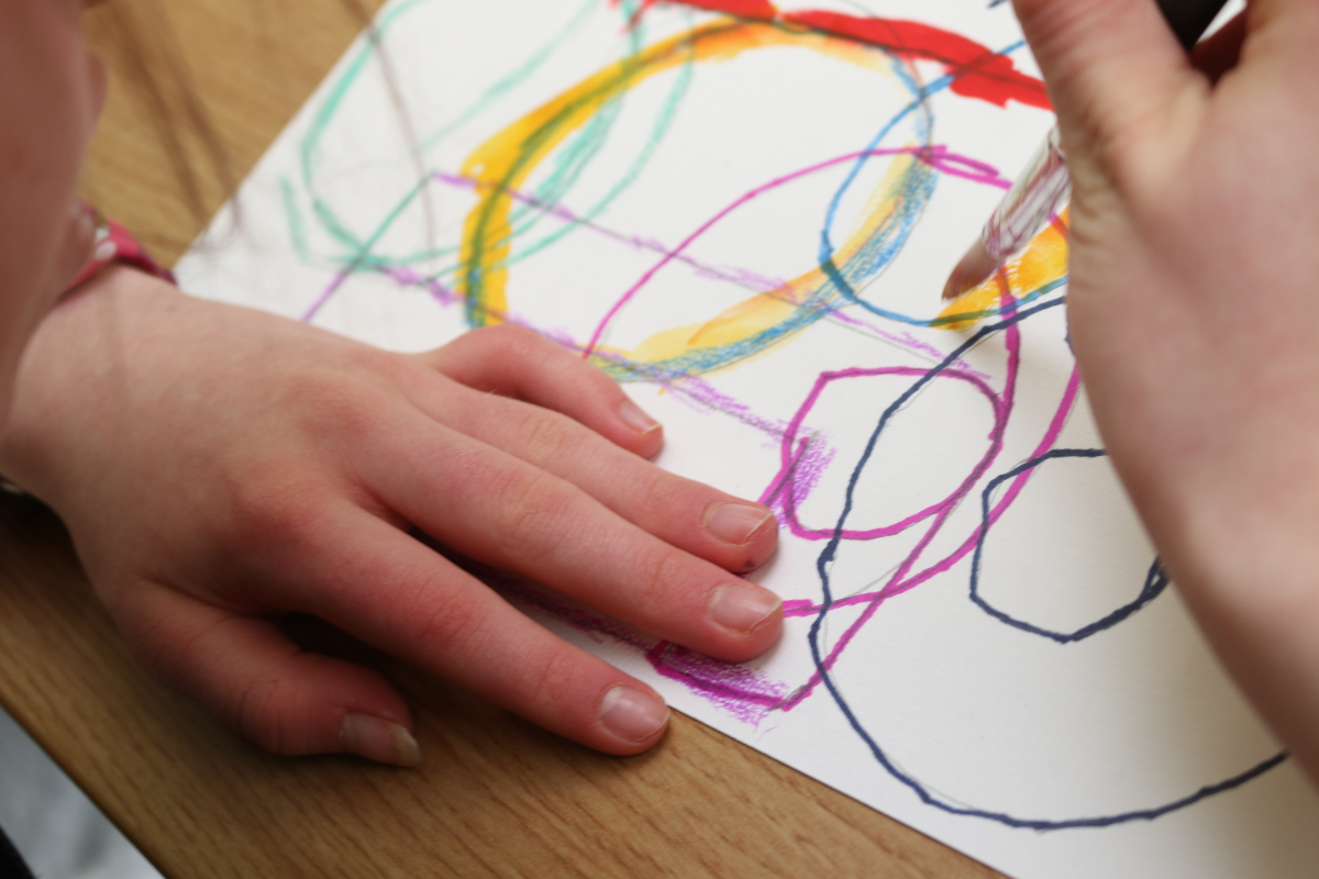 children's hand drawing circles on a piece of papter