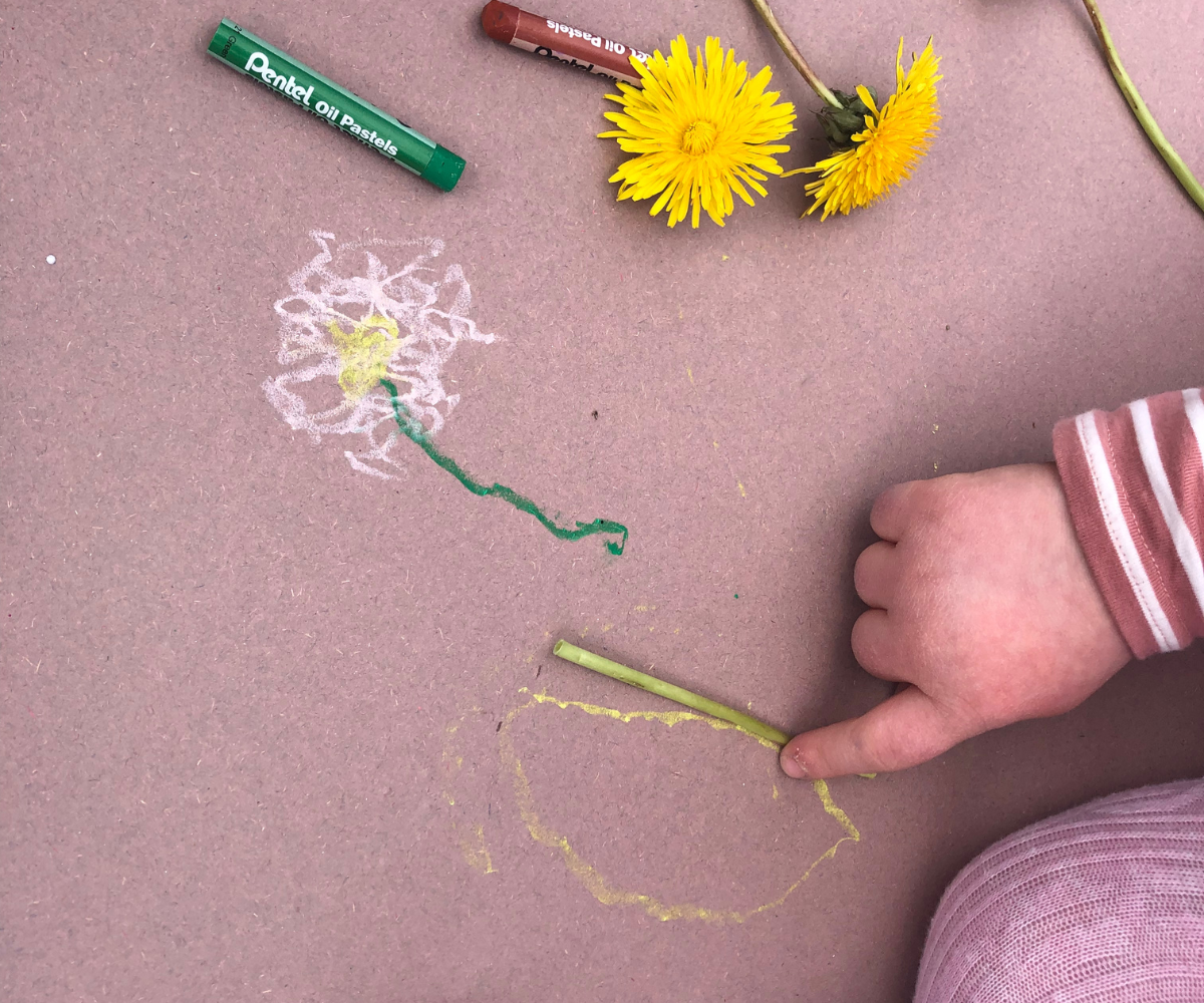 Childs hand drawing with chalk and daisies on the floor